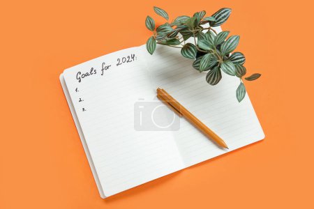 Téléchargez les photos : Carnet avec liste vide à faire, plante d'intérieur et stylo sur fond orange. Nouveaux objectifs de l'année - en image libre de droit