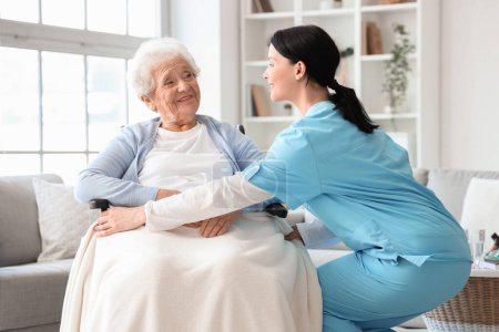 Foto de Enfermera cuidando a una mujer mayor en silla de ruedas en casa - Imagen libre de derechos