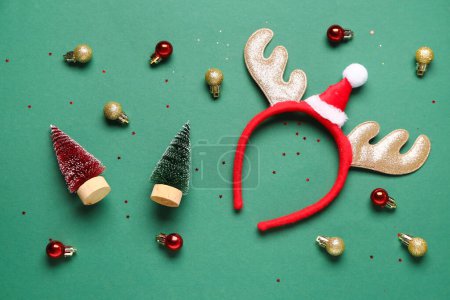 Foto de Lindos cuernos de reno con bolas de Navidad sobre fondo verde - Imagen libre de derechos