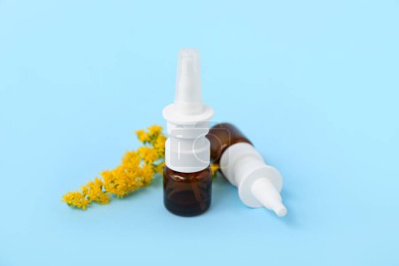 Photo for Bottles of nasal drops with flowers on blue background - Royalty Free Image