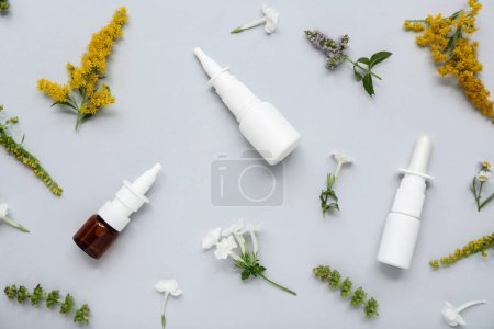 Photo for Bottles of nasal drops with different flowers on grey background - Royalty Free Image