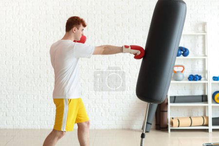 Téléchargez les photos : Jeune boxeur rousse sac de boxe dans la salle de gym - en image libre de droit