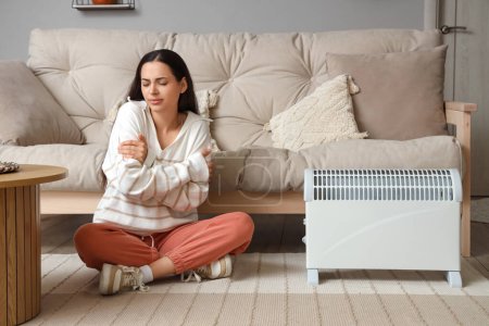 Photo for Young woman warming near radiator at home - Royalty Free Image
