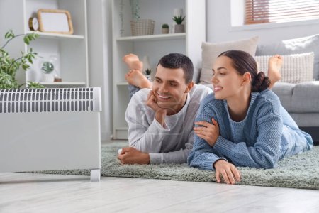 Photo for Young couple warming near radiator at home - Royalty Free Image