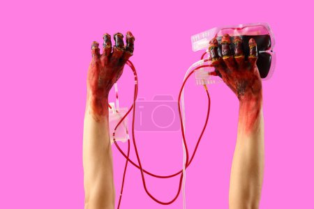 Téléchargez les photos : Mains zombies ensanglantées avec du sang sur fond rose. Fête d'Halloween - en image libre de droit
