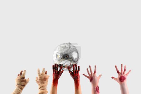 Téléchargez les photos : Zombie et maman mains tenant boule disco sur fond blanc. Fête d'Halloween - en image libre de droit