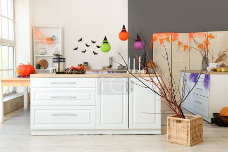 Photo for Interior of light kitchen decorated for Halloween with white counters and pumpkins - Royalty Free Image