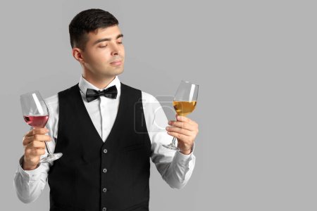 Photo for Young sommelier with glasses of wine on grey background - Royalty Free Image