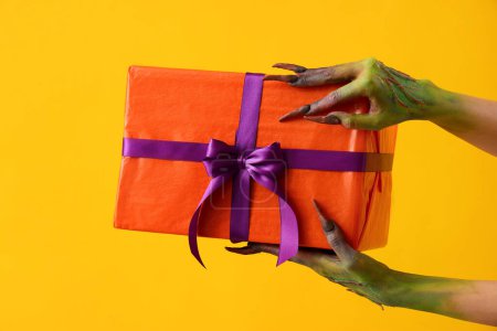 Téléchargez les photos : Sorcière avec cadeau sur fond jaune. Fête d'Halloween - en image libre de droit