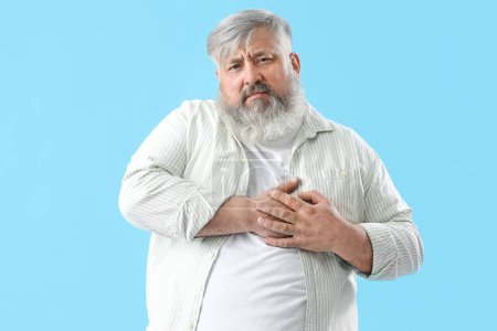 Photo for Senior man having heart attack on blue background - Royalty Free Image