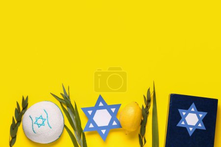 Foto de Cuatro especies (lulav, hadas, arava, etrog) como símbolos del festival Sukkot, Torá, kippa y papel David estrella sobre fondo amarillo - Imagen libre de derechos