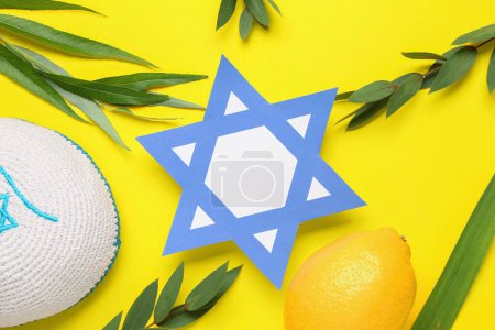 Foto de Cuatro especies (lulav, hadas, arava, etrog) como símbolos del festival Sukkot y papel estrella David sobre fondo amarillo - Imagen libre de derechos