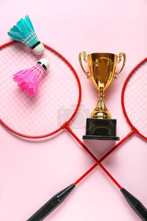 Photo for Gold cup with badminton rackets and shuttlecocks on pink background - Royalty Free Image