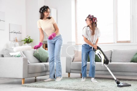 Foto de Niña y su madre con rizadores de pelo limpiando en casa - Imagen libre de derechos