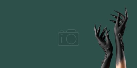 Téléchargez les photos : Mains noires de sorcière avec griffes sur fond vert avec espace pour le texte. Fête d'Halloween - en image libre de droit