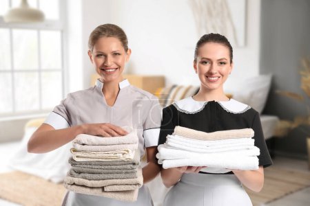 Photo for Portrait of beautiful chambermaids with clean towels in bedroom - Royalty Free Image