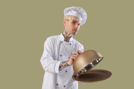 Téléchargez les photos : Chef masculin tatoué avec cloche sur fond vert - en image libre de droit
