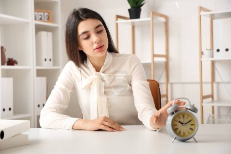 Photo for Businesswoman touching alarm clock in office. Time management concept - Royalty Free Image