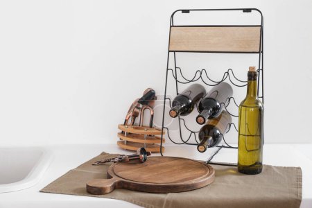 Téléchargez les photos : Comptoir de cuisine blanche avec bouteilles de vin sur pied et planche à découper - en image libre de droit