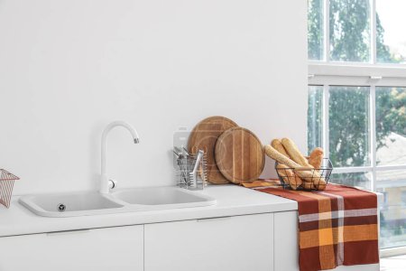 Téléchargez les photos : Comptoirs de cuisine blancs avec évier, planches à découper et baguettes - en image libre de droit