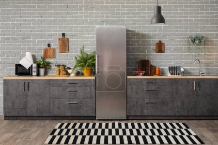 Téléchargez les photos : Intérieur de la cuisine moderne avec comptoirs gris, réfrigérateur et plantes d'intérieur - en image libre de droit