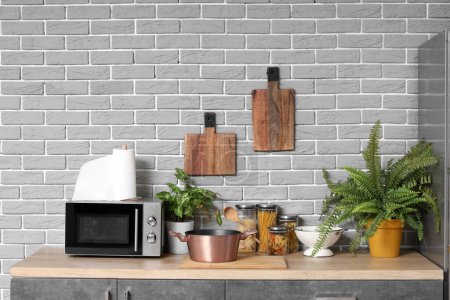 Téléchargez les photos : Comptoir en bois avec four à micro-ondes, plantes d'intérieur et ustensiles dans la cuisine moderne - en image libre de droit