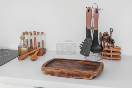 Téléchargez les photos : Planche à découper en bois et ustensiles sur comptoir de cuisine blanc, gros plan - en image libre de droit