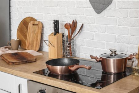 Téléchargez les photos : Comptoir de cuisine en bois avec planches à découper, cuisinière électrique et ustensiles - en image libre de droit