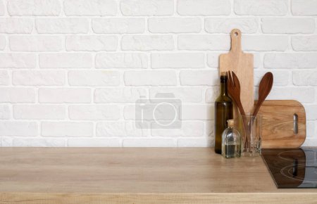 Téléchargez les photos : Comptoir en bois avec planches à découper et ustensiles près du mur de briques blanches - en image libre de droit