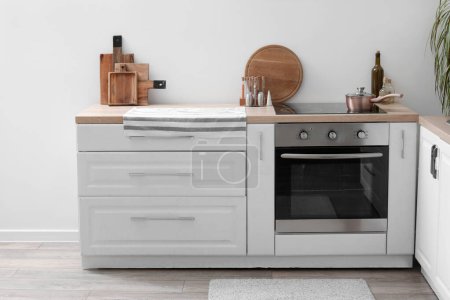 Téléchargez les photos : Comptoirs de cuisine blancs avec planches à découper, cuisinière électrique et four - en image libre de droit