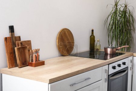 Téléchargez les photos : Comptoir de cuisine blanc avec planches à découper, cuisinière électrique et condiments - en image libre de droit