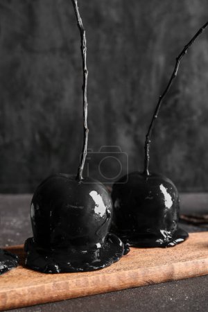 Photo for Wooden board with tasty caramel apples for Halloween on black background - Royalty Free Image