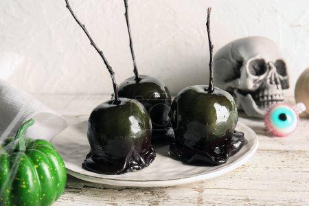 Photo for Plate of tasty caramel apples for Halloween, spider web and pumpkin on table - Royalty Free Image