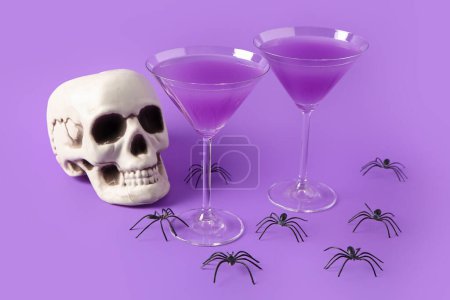Téléchargez les photos : Lunettes de délicieux cocktail avec crâne et araignées pour la célébration d'Halloween sur fond violet - en image libre de droit