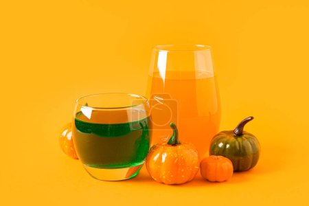 Téléchargez les photos : Verres de délicieux cocktails avec des citrouilles pour la célébration d'Halloween sur fond orange - en image libre de droit