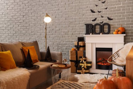 Photo for Interior of festive living room with fireplace, grey sofa and Halloween decorations - Royalty Free Image