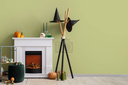 Photo for White fireplace with Halloween pumpkins and decorations near green wall - Royalty Free Image
