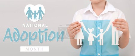 Téléchargez les photos : Bannière pour le Mois national de l'adoption avec garçon tenant la figure de papier de la famille - en image libre de droit