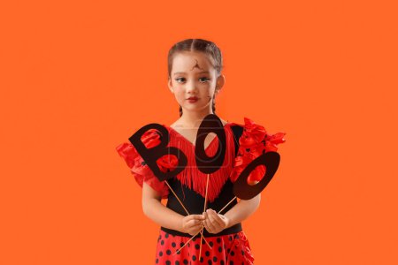 Téléchargez les photos : Petite fille asiatique habillée pour Halloween avec le mot BOO sur fond orange - en image libre de droit