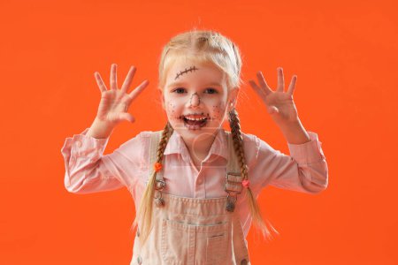 Téléchargez les photos : Petite fille mignonne habillée pour Halloween comme épouvantail sur fond orange - en image libre de droit