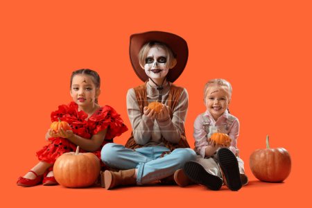 Téléchargez les photos : Petits enfants habillés pour Halloween avec des citrouilles sur fond orange - en image libre de droit