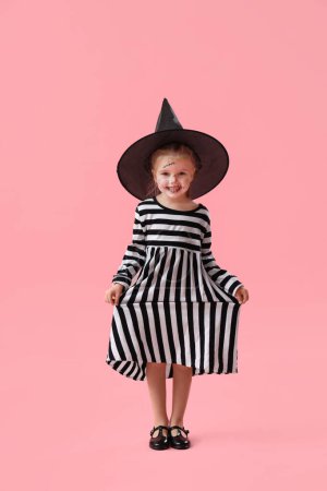 Téléchargez les photos : Petite fille mignonne habillée pour Halloween comme sorcière sur fond rose - en image libre de droit