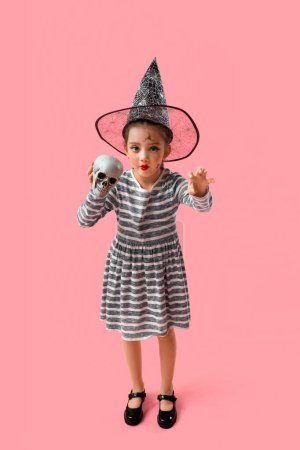 Téléchargez les photos : Petite fille mignonne habillée pour Halloween en sorcière avec crâne sur fond rose - en image libre de droit