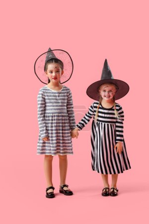 Téléchargez les photos : Petites filles habillées pour Halloween comme des sorcières sur fond rose - en image libre de droit
