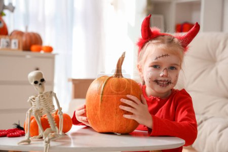 Téléchargez les photos : Petite fille avec citrouille célébrant Halloween à la maison - en image libre de droit