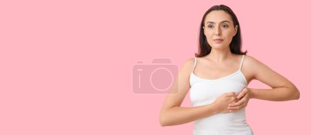 Téléchargez les photos : Jeune femme vérifiant son sein sur fond rose avec de l'espace pour le texte - en image libre de droit
