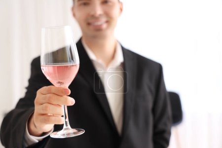 Photo for Young sommelier with glass of pink wine in kitchen, closeup - Royalty Free Image