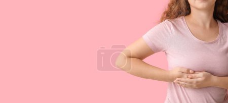 Téléchargez les photos : Jeune femme vérifiant son sein sur fond rose avec de l'espace pour le texte - en image libre de droit