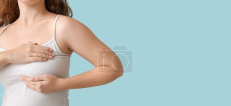 Téléchargez les photos : Jeune femme vérifiant sa poitrine sur fond bleu clair avec de l'espace pour le texte - en image libre de droit