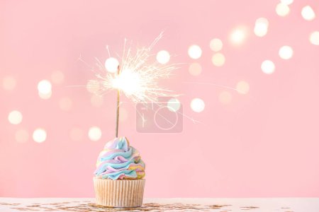Photo for Tasty birthday cupcake with sparkler and decor on color background - Royalty Free Image